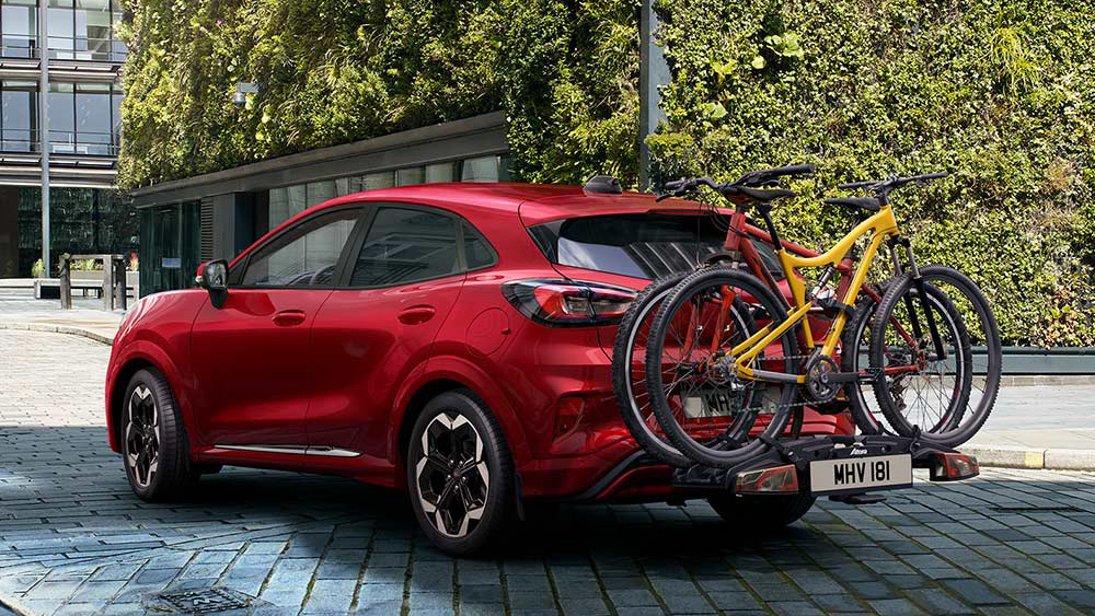 Roter Ford Puma fährt mit Fahrrad hinten auf der Straße